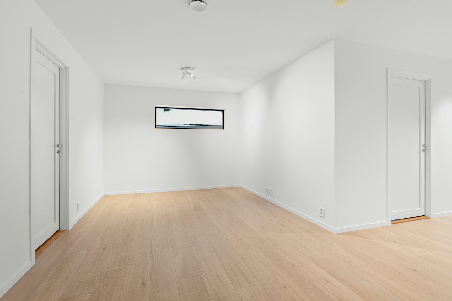 Empty room with hardwood floors and white walls.